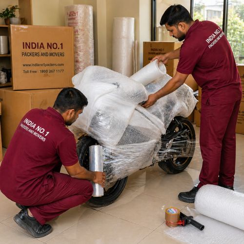 Professional bike shifting services in Delhi with movers securely wrapping a motorcycle using bubble wrap for safe transportation